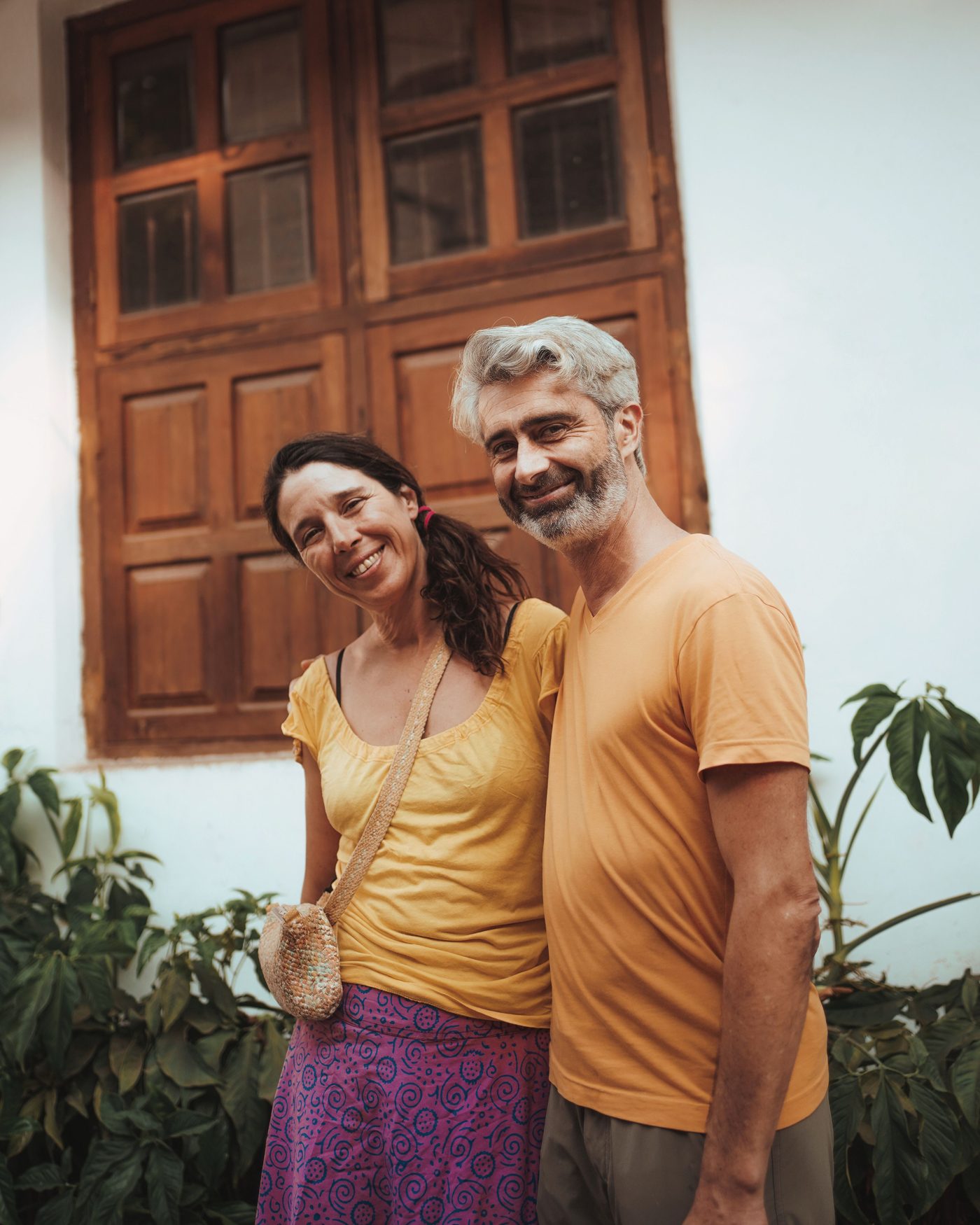 Mature couple smiling outdoors by a garden window
